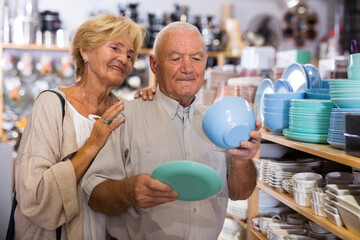 Portrait of an elderly couple in tableware store - making a selection of new plates and cups