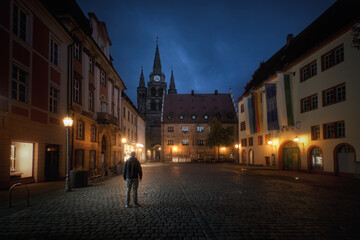 Square of old German town with street lamps at night a man standing from the back. Ansbach, Bavaria Region Middle Franconia, Germany