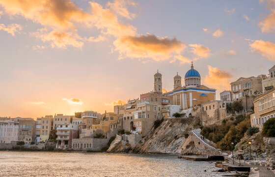 View of the village with the Greek Orthodox church of Agios Nikolaos, Asteria Beach, at sunset with atmospheric clouds, Ermoupoli, Syros, Cyclades, Greece, Europe
