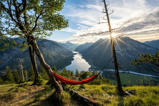 View of Plansee from Schoenjoechl with orange hammock, at sunset, sun star, panoramic view of mountains with lake, Plansee, Tyrol, Austria, Europe