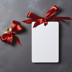 Empty white price tag or gift card mockup with a red gift ribbon bow on a gray wall background with decorations,