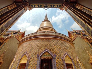 Wide angle of golden pagoda and the curved walkway around the circular cloister of Wat Ratchabophit in Bangkok, THAILAND.
