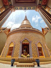 Wide angle of golden pagoda and the curved walkway around the circular cloister of Wat Ratchabophit in Bangkok, THAILAND.