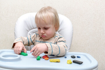 Cute little child boy playing at home, molding multi-colored plasticine.Childrens hands sculpts with colored clay stucco. Play dough,clay modeling.art creativity, craft at daycare, kindergarten