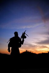 Fototapeta na wymiar silhouette of a soldier with a rifle in sunset