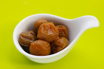 Pickled plums on green background.
