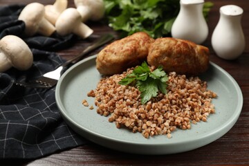 Tasty buckwheat with fresh parsley and cutlets on wooden table
