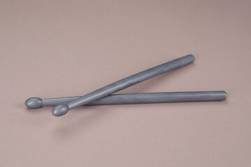 Two gray drum sticks on dusty rose background
