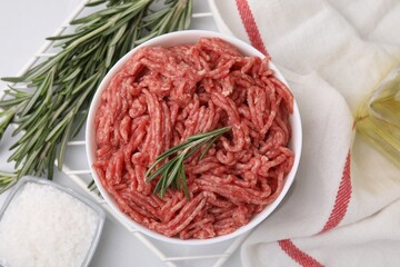 Flat lay composition with fresh raw ground meat and rosemary in bowl on light table