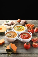 Tasty broth, cream soups in bowls and ingredients on old wooden table
