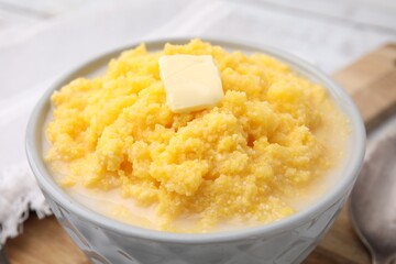 Tasty cornmeal with butter in bowl on table, closeup