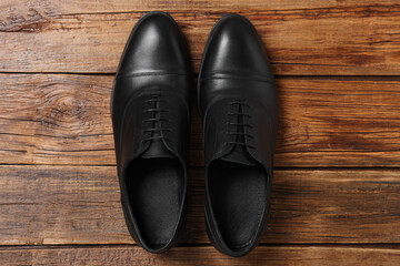 Pair of black leather men shoes on wooden background, top view