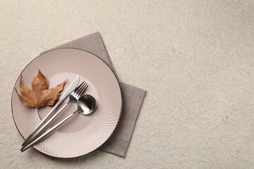 Stylish table setting with cutlery and dry leaf on light surface, top view. Space for text