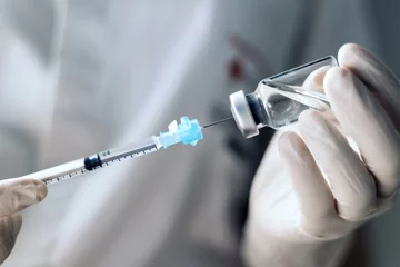 Fotobehang injecting injection vaccine vaccination medicine covid into a syringe woman nurse. Close-up © PEDROMERINO