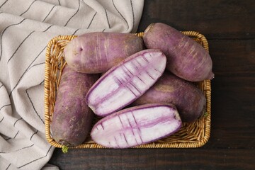 Purple daikon radishes in wicker basket on wooden table, top view