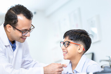 Boy doing an eye test checking examination with optometrist in the optical shop, Smiling...