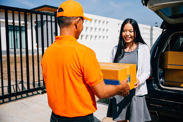 Home delivery concept portrayed as a courier delivers a cardboard parcel to a smiling woman...