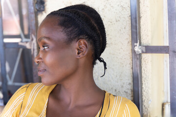 portrait of a young african woman, braids hairstyle, burglar bars inn the back at the window