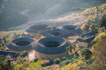 Aerial view of Tianluokeng Tulou cluster with evening mist.