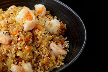 Fried rice with shrimp and sesame, on a dark background