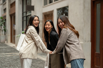 Young attractive, fun Asian girls are enjoying shopping on the shopping street in the city together.