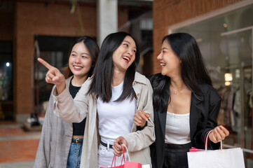 Group of attractive, fun Asian girls in trendy clothes are enjoying shopping in the city.
