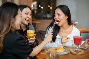 Group of cheerful and pretty Asian female friends are enjoying eating food and hanging out at a cafe