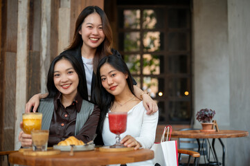 Three attractive young Asian women are sitting at a table in a restaurant together, hanging out