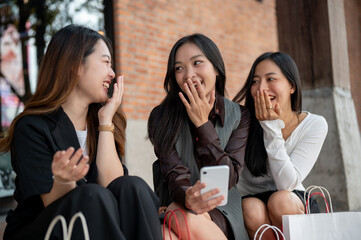 Group of happy young Asian girls are enjoying chit chat while resting on the stairs after shopping.