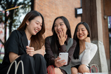 Group of happy young Asian girls are enjoying chit chat while resting on the stairs after shopping.