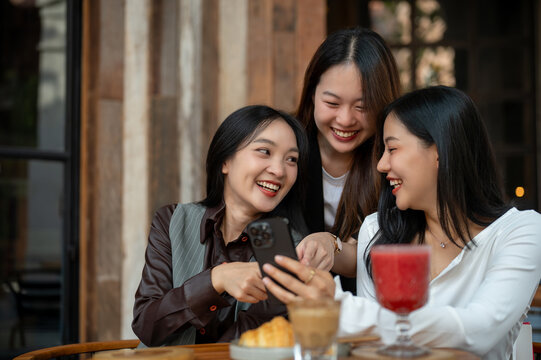 Group of beautiful Asian female friends are enjoying chit chat, gossiping, hanging out at a cafe.