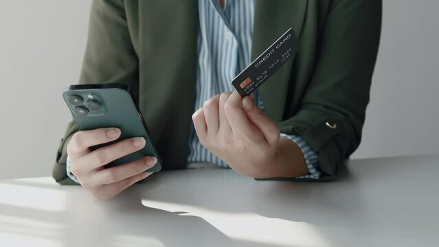 Person holding a credit card, she uses a credit card to pay for goods and services online, the concept of using a credit card for online shopping, ordering goods and services on the website.