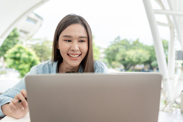Beautiful Asian woman female student excited checking language test results on laptop. Smile girl happy study online. book in college campus. Portrait female on international Asia University