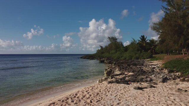 Low angle drone shot of rocky white sand beach at Tinian island
