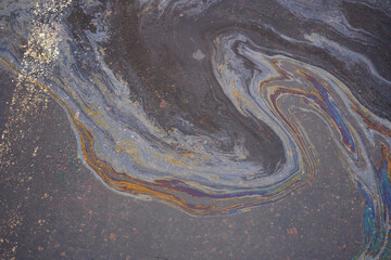 Oil, gasoline, or oil spill on wet asphalt with a parking lot and a dividing line