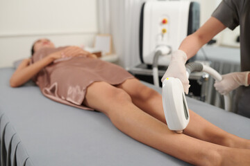 Beautician removing hair on legs of client with laser