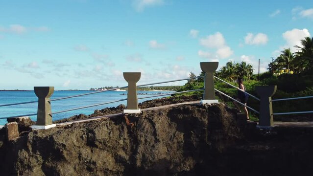 Drone shot of a girl walking towards the cliff of Taga beach, Tinian Island