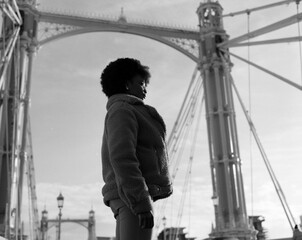 Alternative black woman standing on historical bridge structure.