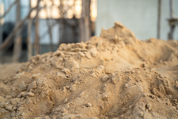 Pile of fine sand for building the house that stack on the ground with construction site as blurred background. Industrial object photo, close-up and selective focus. - obrazy, fototapety, plakaty