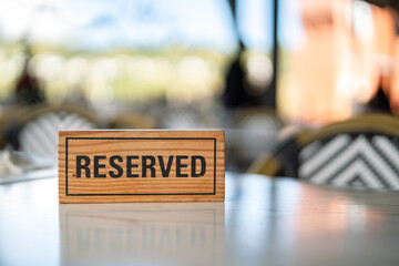 A wooden reserved sign that placed on the dining table at the luxury restaurant for booking the...