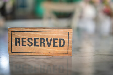 A wooden reserved sign that placed on the dining table at the luxury restaurant for booking the seat. Sign and symbol object photo.