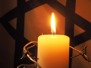 Flag of Israel, barbed wire and burning candle on black background. Holocaust memory day
