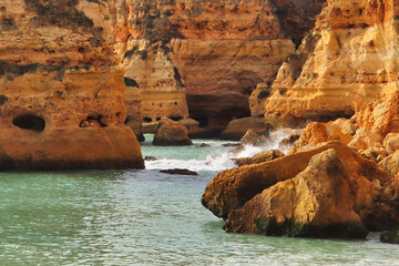 Water splashing on large rocks in the ocean on a sunny winter day at a beach in southern Portugal.