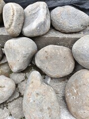Closeup of irregular smooth gray stones piled up at a construction site vertical background