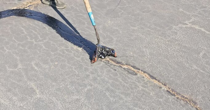 During worker patcher performs coated filling asphalt cracks sealing bitumen emulsion road surface restoration work