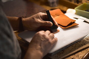man learning to work with leather stitching punch, close up cropped side view photo. focus on sewing tool and arms, hands - Powered by Adobe