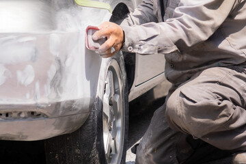 hands of a man repairing the bumper of a car