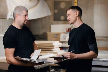 Two carpenters man are discussing project for making wood furniture in workshop. Workplace industry small Business concept