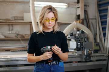 DIY Small Business Production of kitchen furniture. Owner Worker young woman on background CNC milling machine with wooden facade on factory