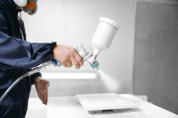 Professional worker Painter staining wood furniture with spray gun. Concept industry carpentry...